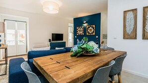 Een moderne woonkamer met een houten eettafel, een blauwe bank en een televisie.