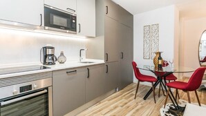 Een moderne keuken met roestvrijstalen apparatuur, een eethoek met rode stoelen en een glazen tafel.