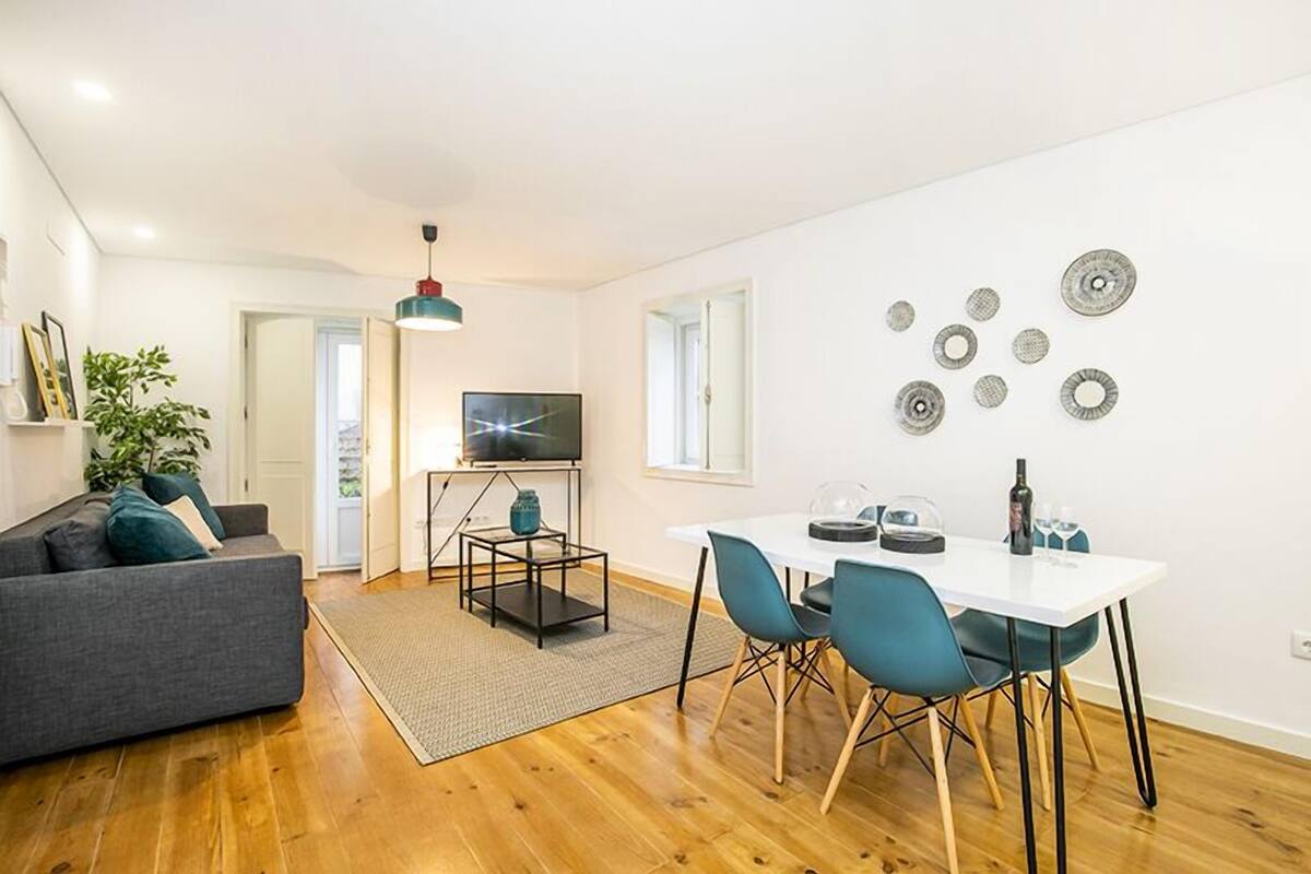 A modern living room with a sofa, a dining table with chairs, a TV, and a coffee table.