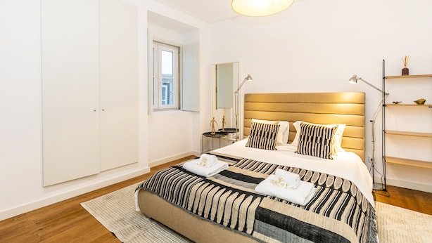 A modern bedroom with a large bed, bedside tables, a wardrobe, and a hanging light fixture. - LxWay Apartments Galeria Alfama (Lisbon)