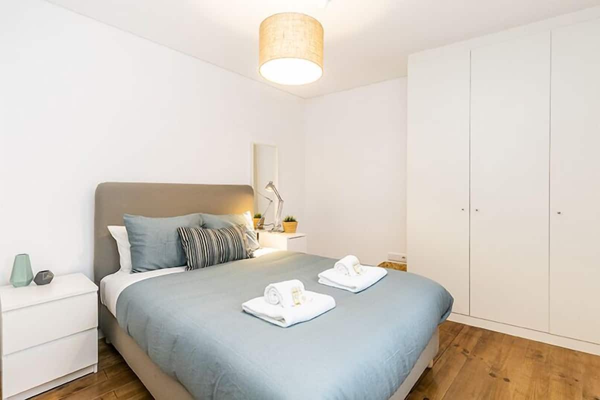 A modern bedroom with a bed, nightstand, bedside lamp, and wardrobe.