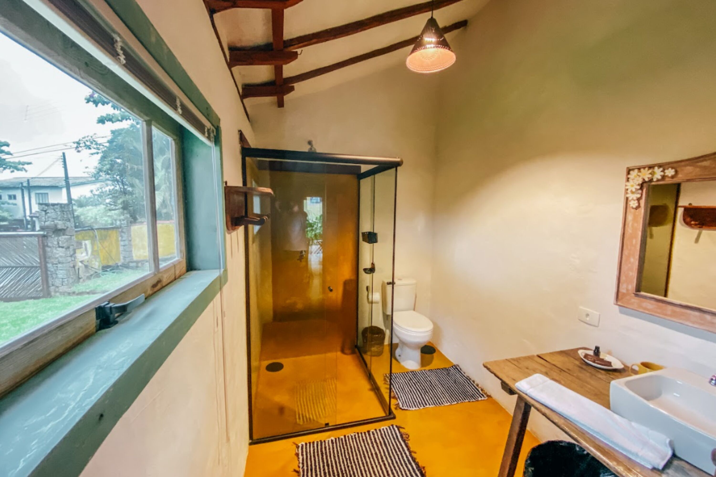 Un baño con ducha, inodoro, lavamanos y ventana con vistas al exterior.