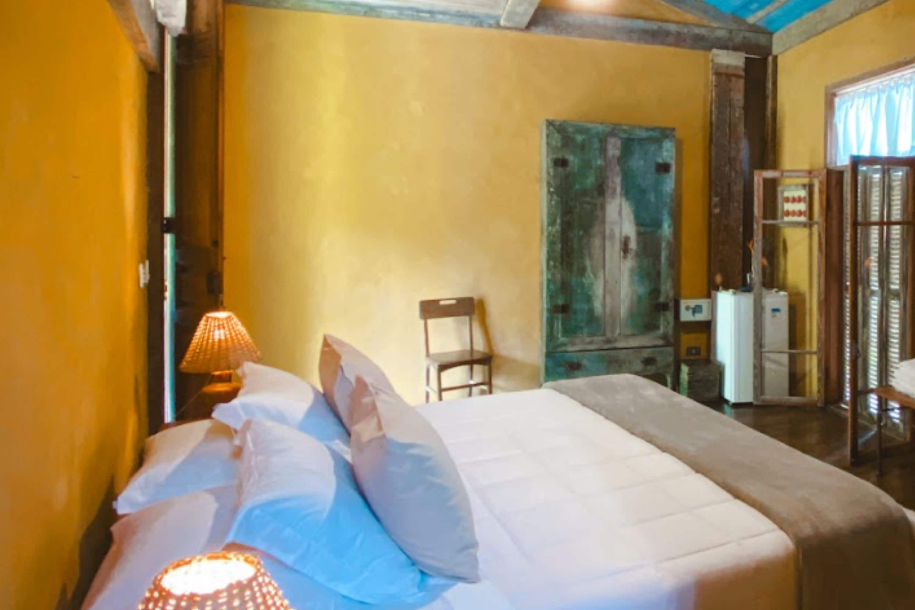 Una habitación con cama, una silla, una lámpara y una puerta.
