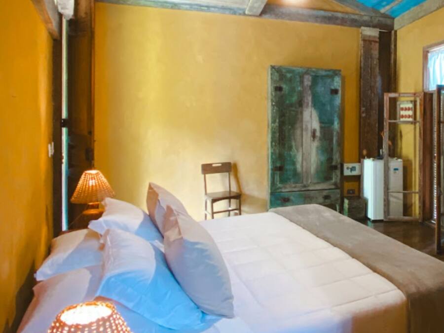 Una habitación con cama, una silla, una lámpara y una puerta.