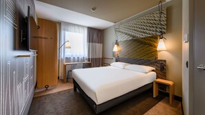 Habitación de hotel moderna con una cama grande, un escritorio, un televisor y una pared con diseño.
