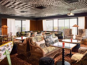 A room with wicker furniture, patterned cushions, and a ceiling with a unique design.