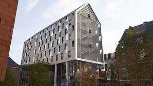 Un bâtiment moderne au design angulaire original, doté de plusieurs étages et de grandes fenêtres.