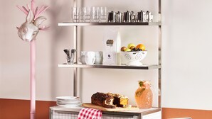Une cuisine avec un réfrigérateur vintage, un batteur sur pied rose et une étagère métallique contenant des ustensiles de cuisine.