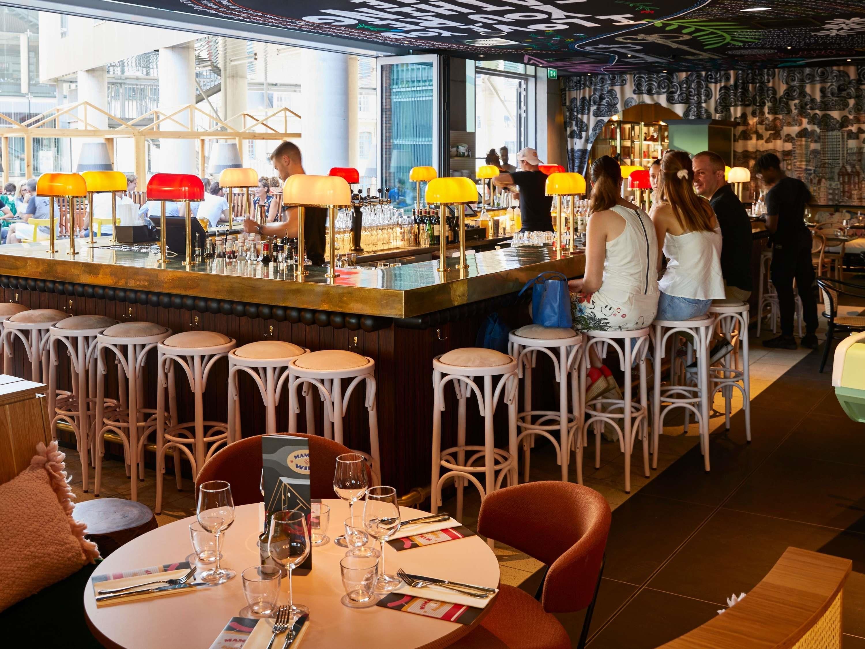 A bar area with stools, a bar counter, and a view of the city.