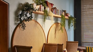 Un'accogliente area relax con mobili in rattan, un tavolino con bevande e una libreria con libri e piante.