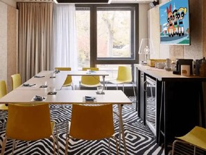 A conference room with a long table, yellow chairs, a zebra-patterned floor, and a painting of cartoon characters on the wall.
