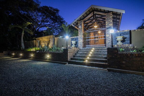 A modern building with a stone facade, a gated entrance, and a staircase leading to the main entrance. - St Lucia Livingston Lodge (St. Lucia)