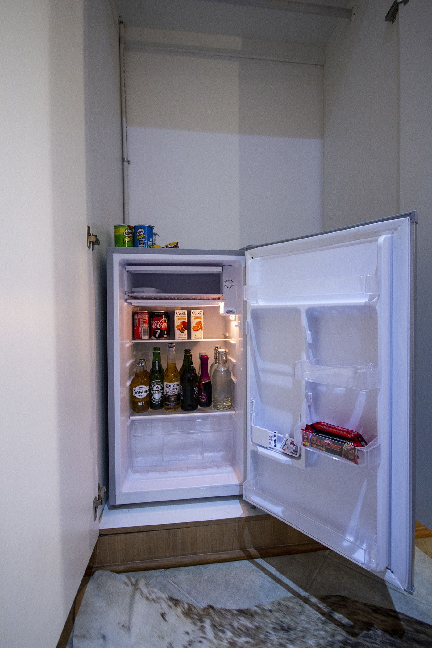 Un refrigerador abierto, lleno de bebidas y aperitivos.