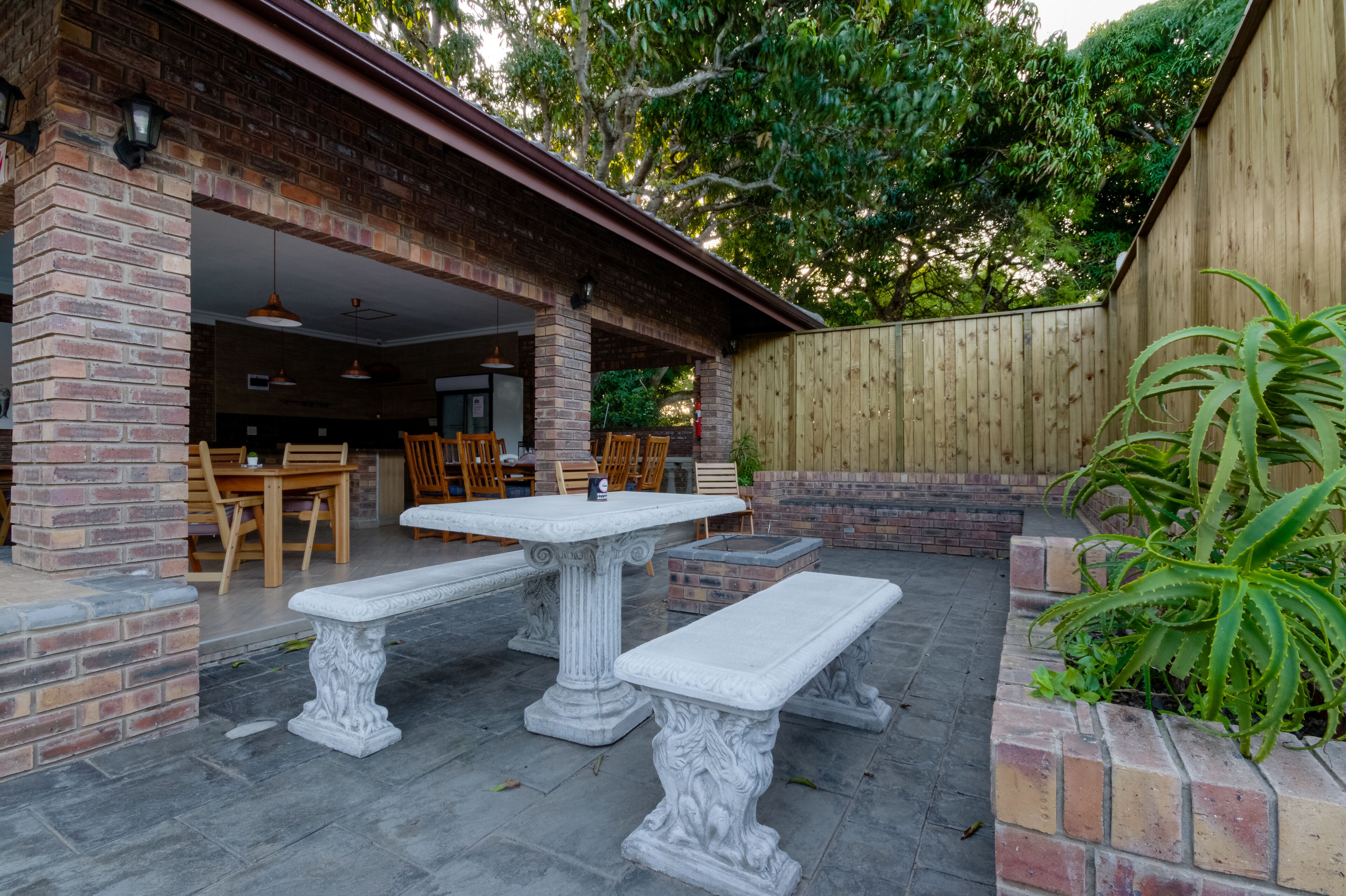 An outdoor patio with a brick wall, a wooden fence, and a table with benches.