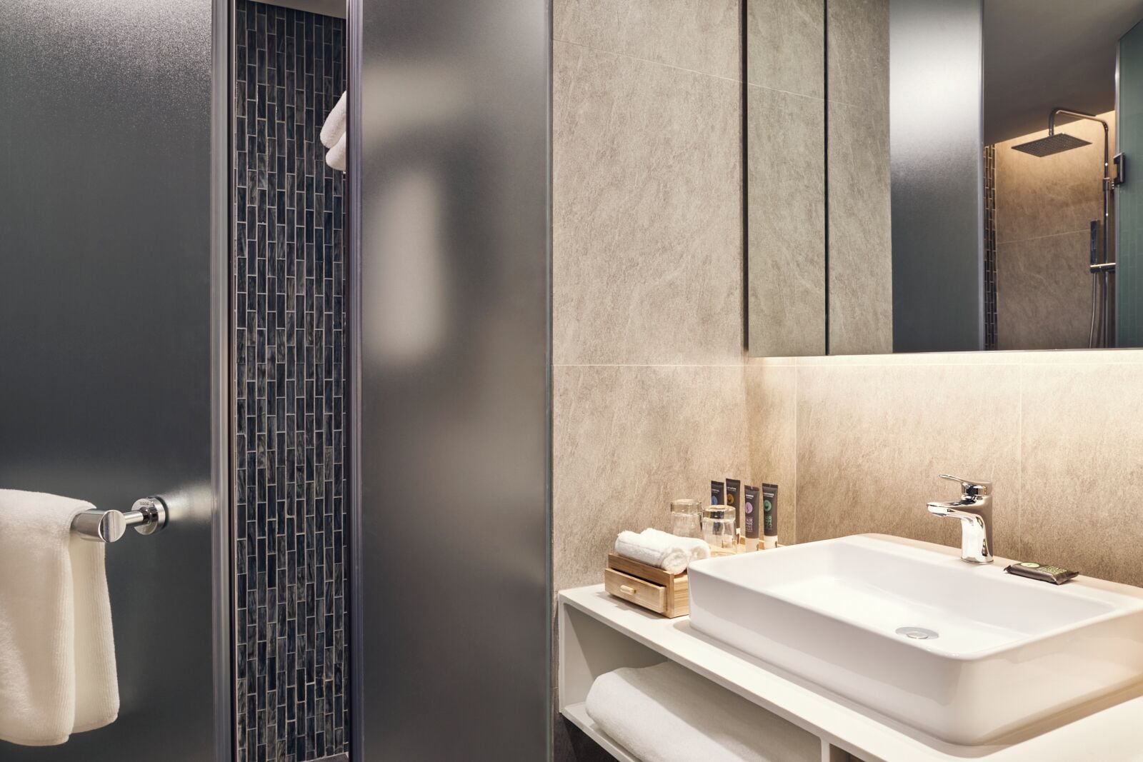 A modern bathroom with a large sink, a mirror, and a towel rack.