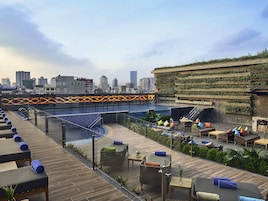 Un bar en la azotea con piscina, zonas de estar y vistas al horizonte de la ciudad.
