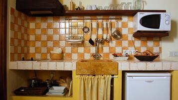 Una cocina con microondas, pileta y diversos utensilios colgados en la pared.