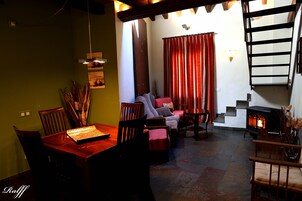 Una sala de estar acogedora con chimenea, un comedor con mesa y sillas de madera, y una escalera con barandilla de madera.