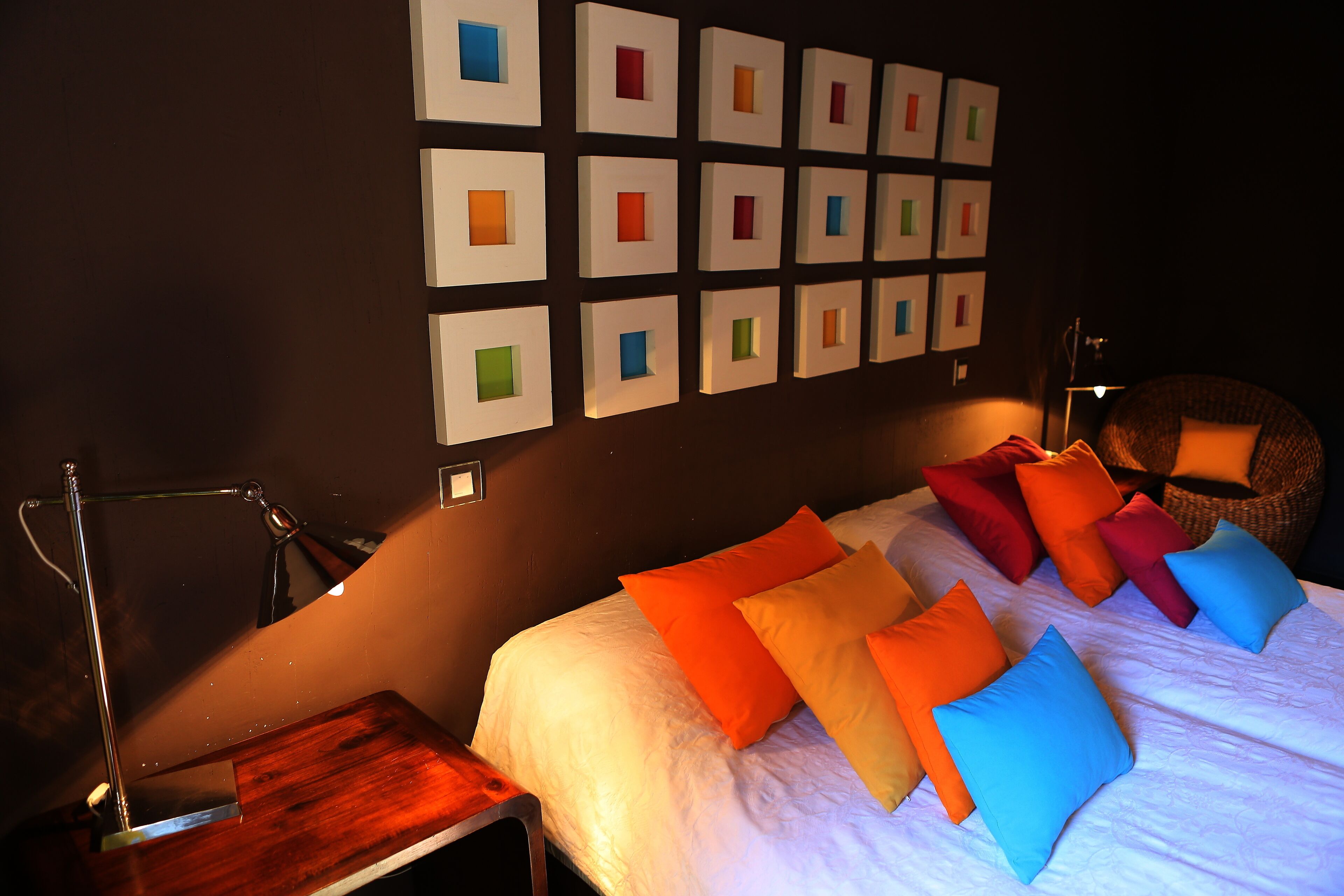 A neatly arranged hotel room with a bed, pillows, a desk, and a wall with framed pictures.