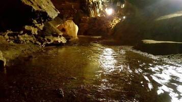 A cave with a stream running through it, illuminated by artificial lights.