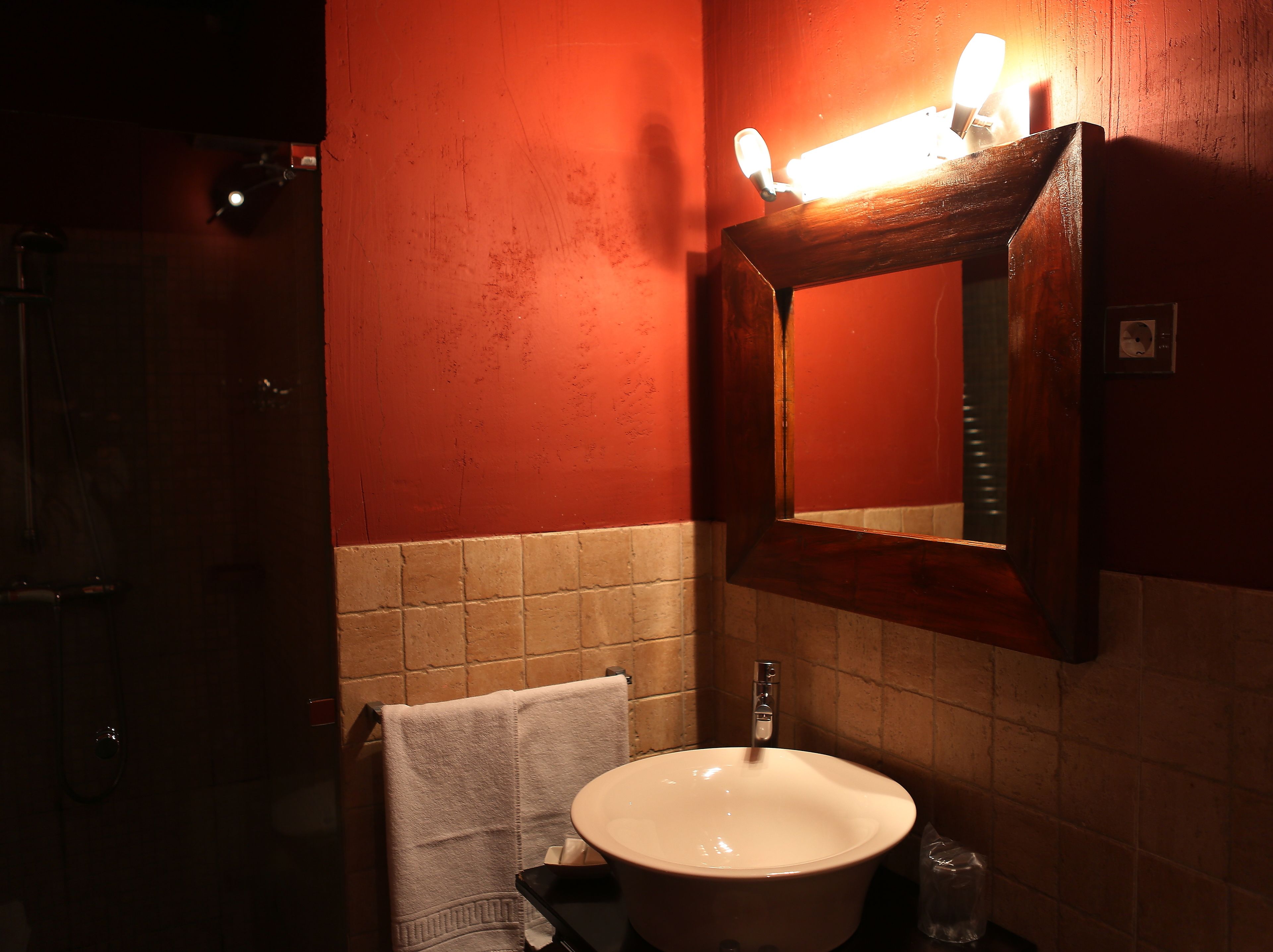 A bathroom with a white sink, a towel hanging on a rack, and a mirror with a light above it.