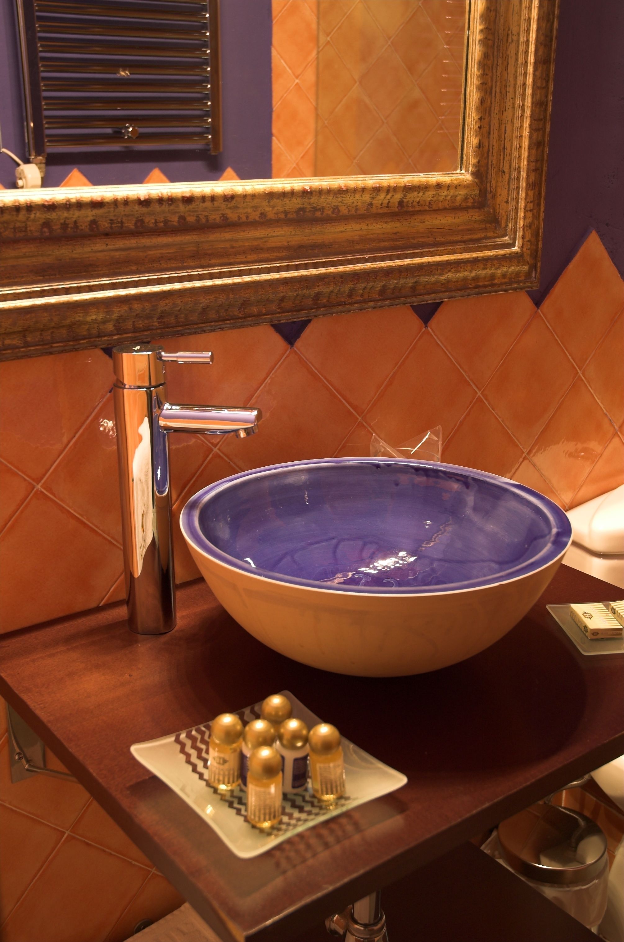A bathroom with a large blue ceramic sink, a chrome faucet, and a decorative plate with golden salt and pepper shakers.