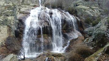 A waterfall cascading over rocky terrain with sparse vegetation.
