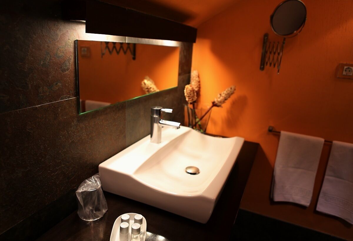Un baño con lavamanos blanco, un espejo y un perchero para toallas.