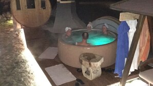 A hot tub in a courtyard with a wooden structure and a tiled floor. - Residence Le Rose (San Giovanni di Fassa)