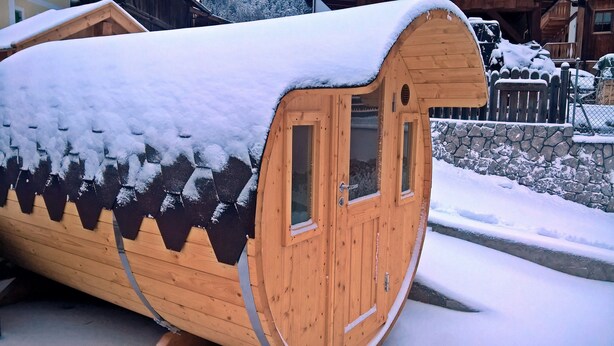 A wooden cabin with a snow-covered roof, a door, and windows. - Residence Le Rose (San Giovanni di Fassa)