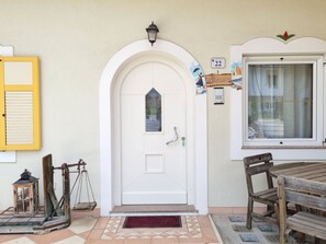 A white door with a small window, a yellow shutter, a lantern, and a wooden bench outside.