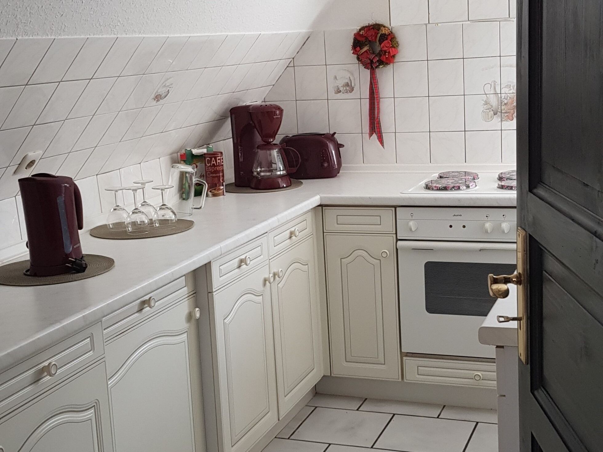 A kitchen with white cabinets, a stove, and a coffee maker.