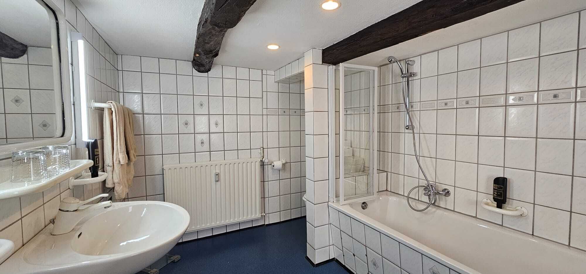 Un baño con bañera, lavamanos, espejo y ducha.