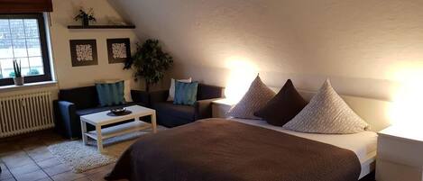 Un dormitorio con una cama grande, un sofá, una mesa de centro y una ventana con vistas.
