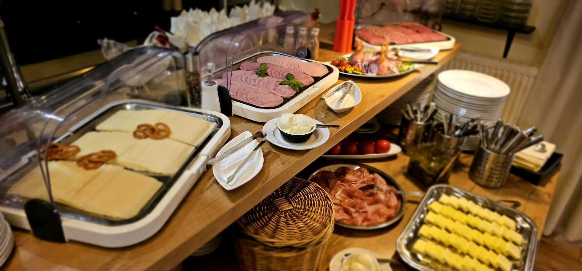 A buffet table with various food items including sliced meats, cheeses, and fruits.
