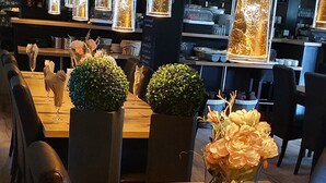 A restaurant interior with a wooden table, chairs, and a vase with flowers. - Hotelbetriebe Güldenhaupt Gmbh (Arnsberg)