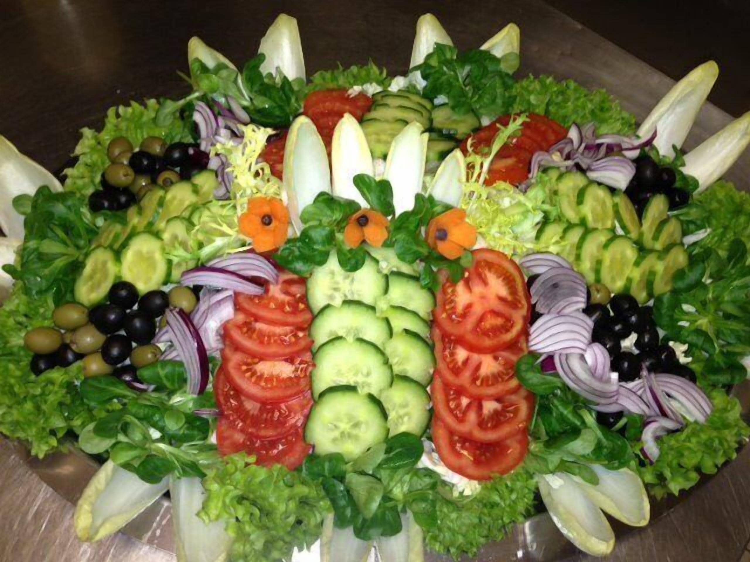 A salad with various vegetables and fruits arranged in a circular pattern.