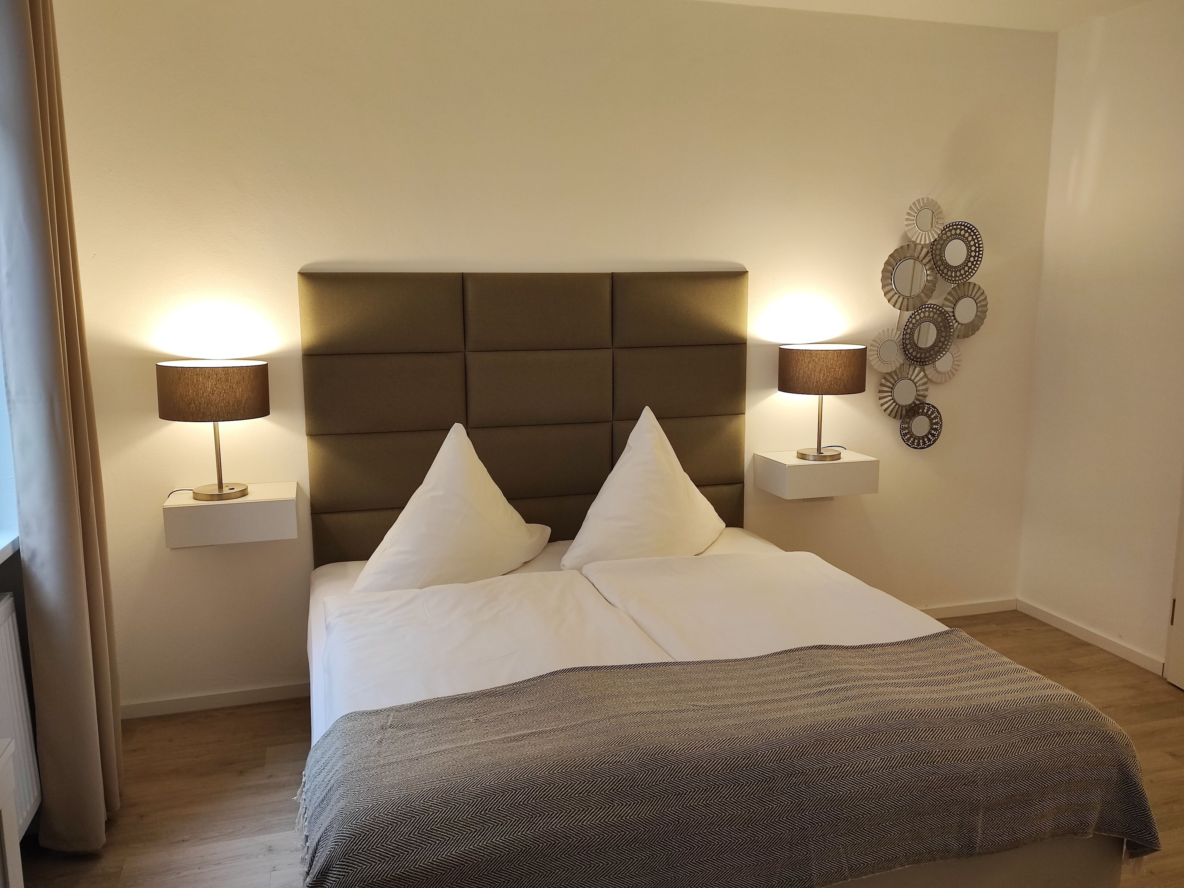 A neatly made bed with two pillows, a headboard, and two bedside lamps.
