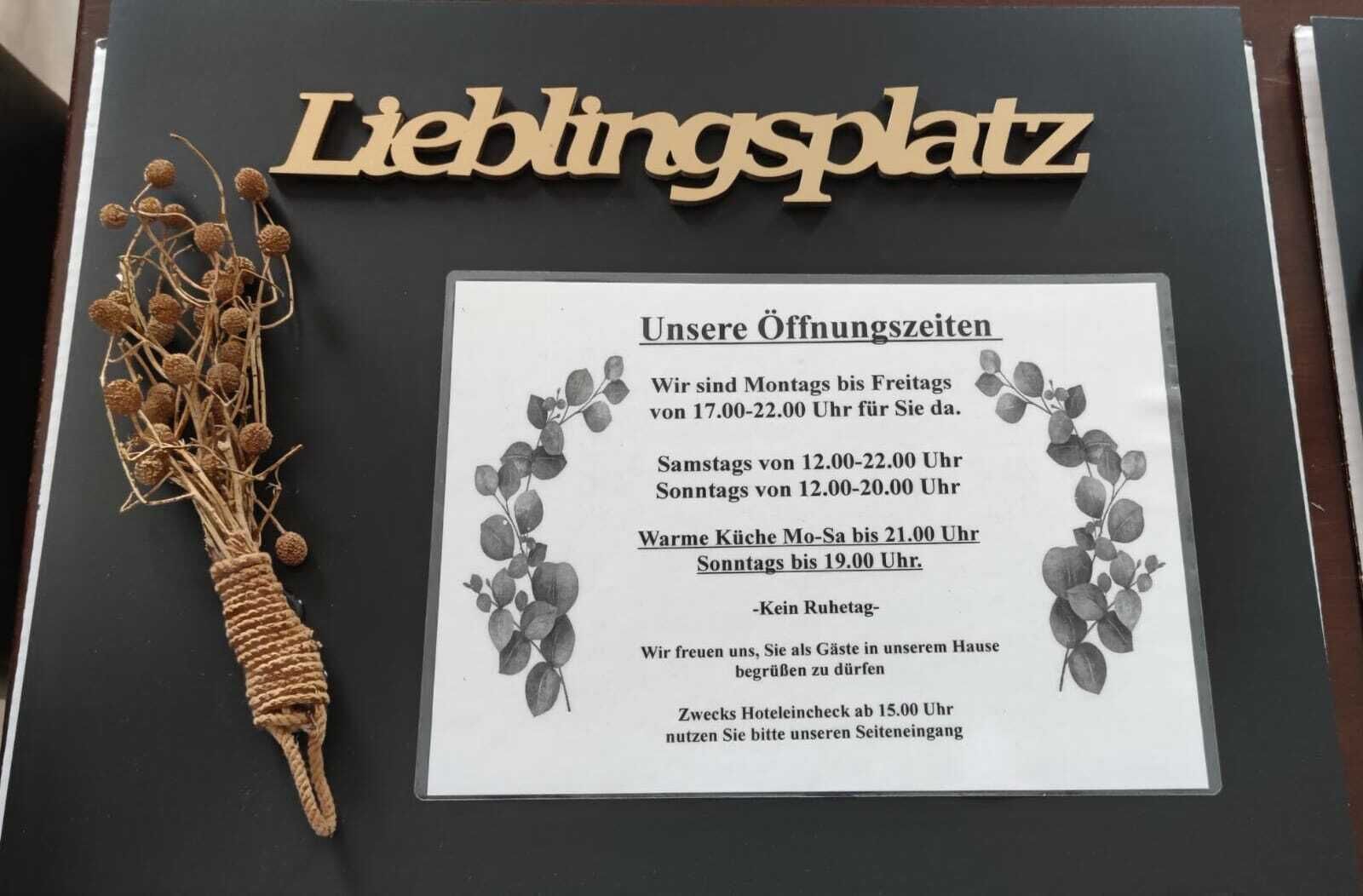 A sign with opening hours and a decorative plant.