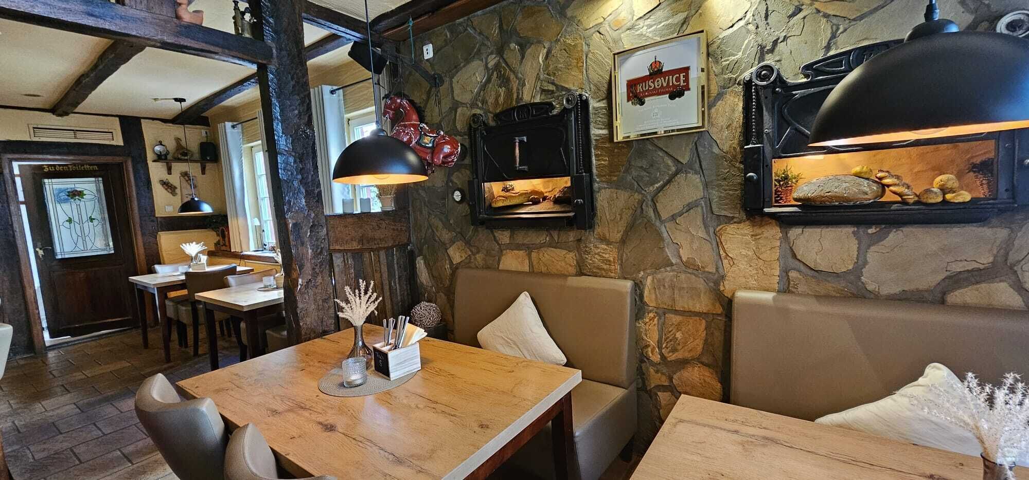 Interior acogedor de un restaurante con paredes de piedra, muebles de madera y una chimenea de piedra.