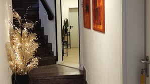 A hallway with a staircase leading to a room, a potted plant, and two framed artworks on the wall. - Hotelbetriebe Güldenhaupt Gmbh (Arnsberg)