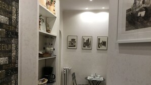 A small, cozy room with a kitchenette, a dining table with chairs, and three framed pictures on the wall. - Le Fate Suites (Rome)