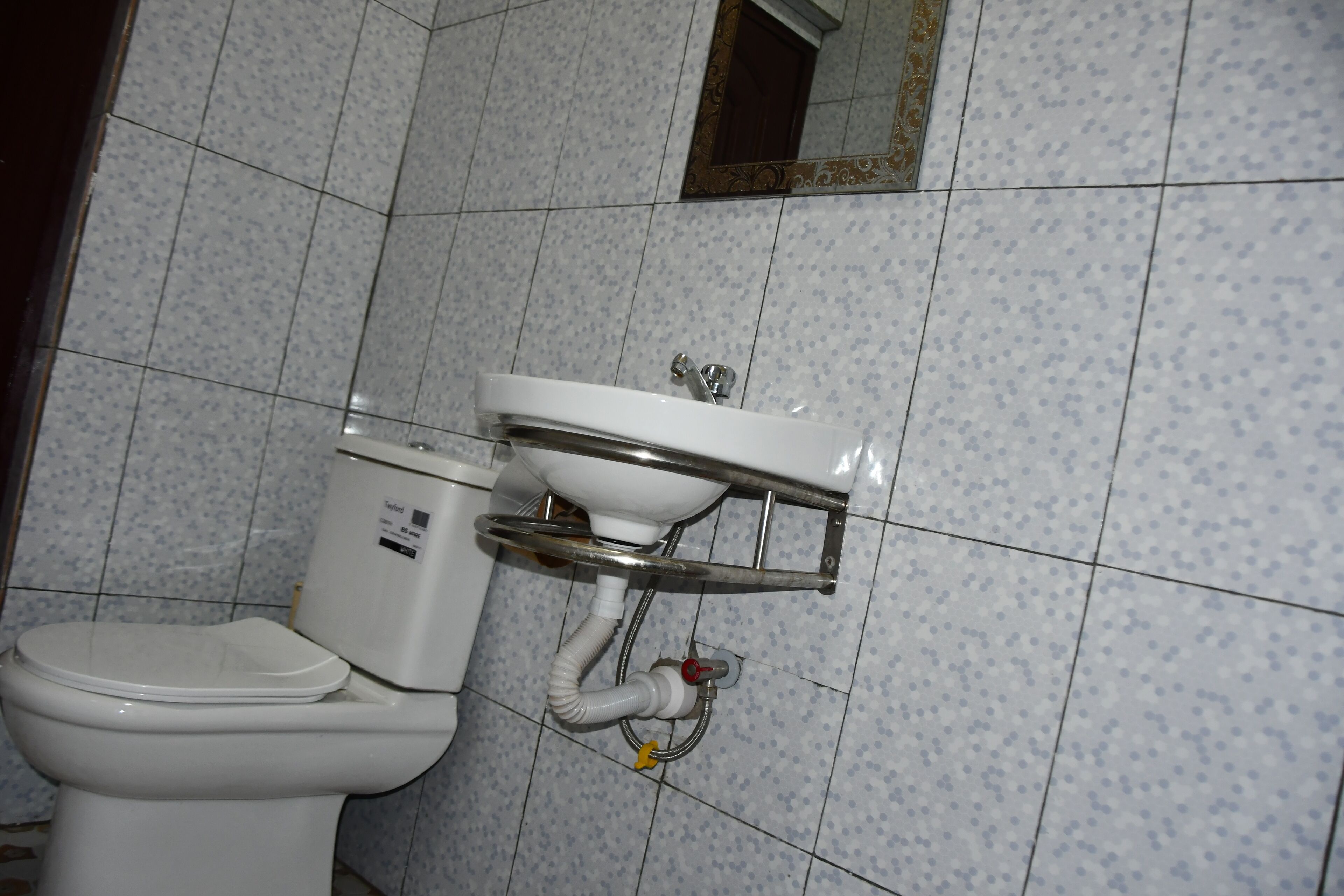 A bathroom with a toilet, sink, and tiled walls.