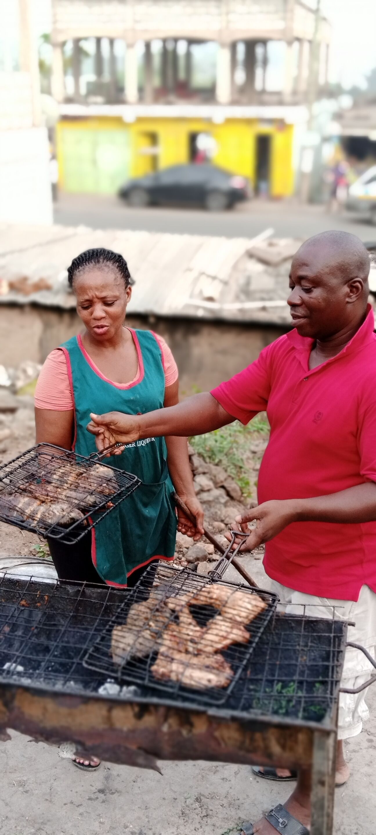 A man and a woman grilling food outdoors.
