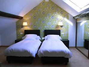 Una habitación con dos camas, un tragaluz y papel tapiz estampado.