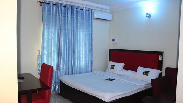 A hotel room with a bed, a desk, and a chair. - TommsVille Hotels (Uyo)