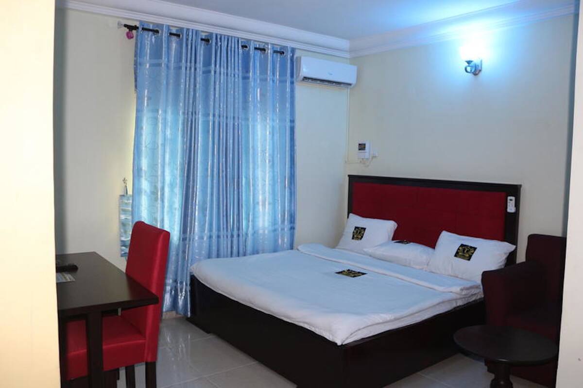 A hotel room with a bed, a desk, and a chair.