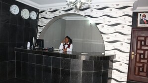 A reception desk with a black marble top, a clock, and a framed picture on the wall. - TommsVille Hotels (Uyo)