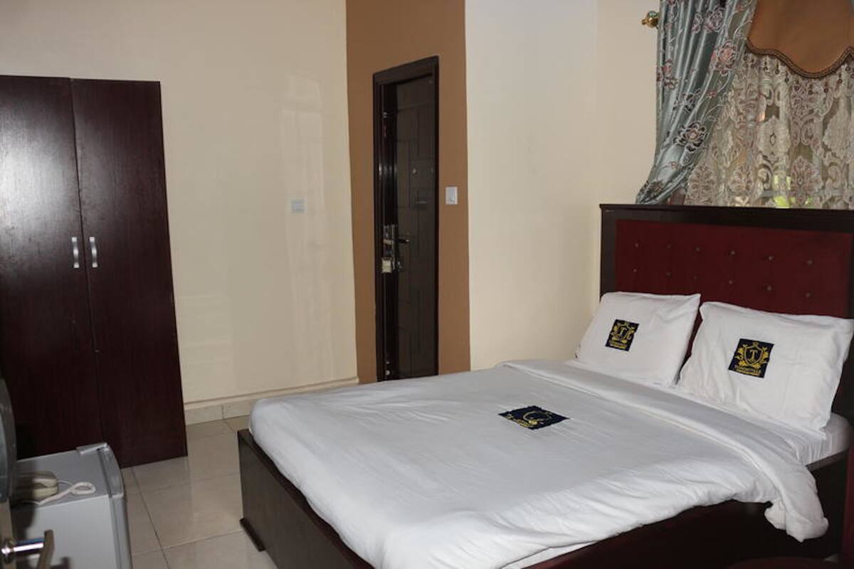 A hotel room with a bed, a wardrobe, and a door.