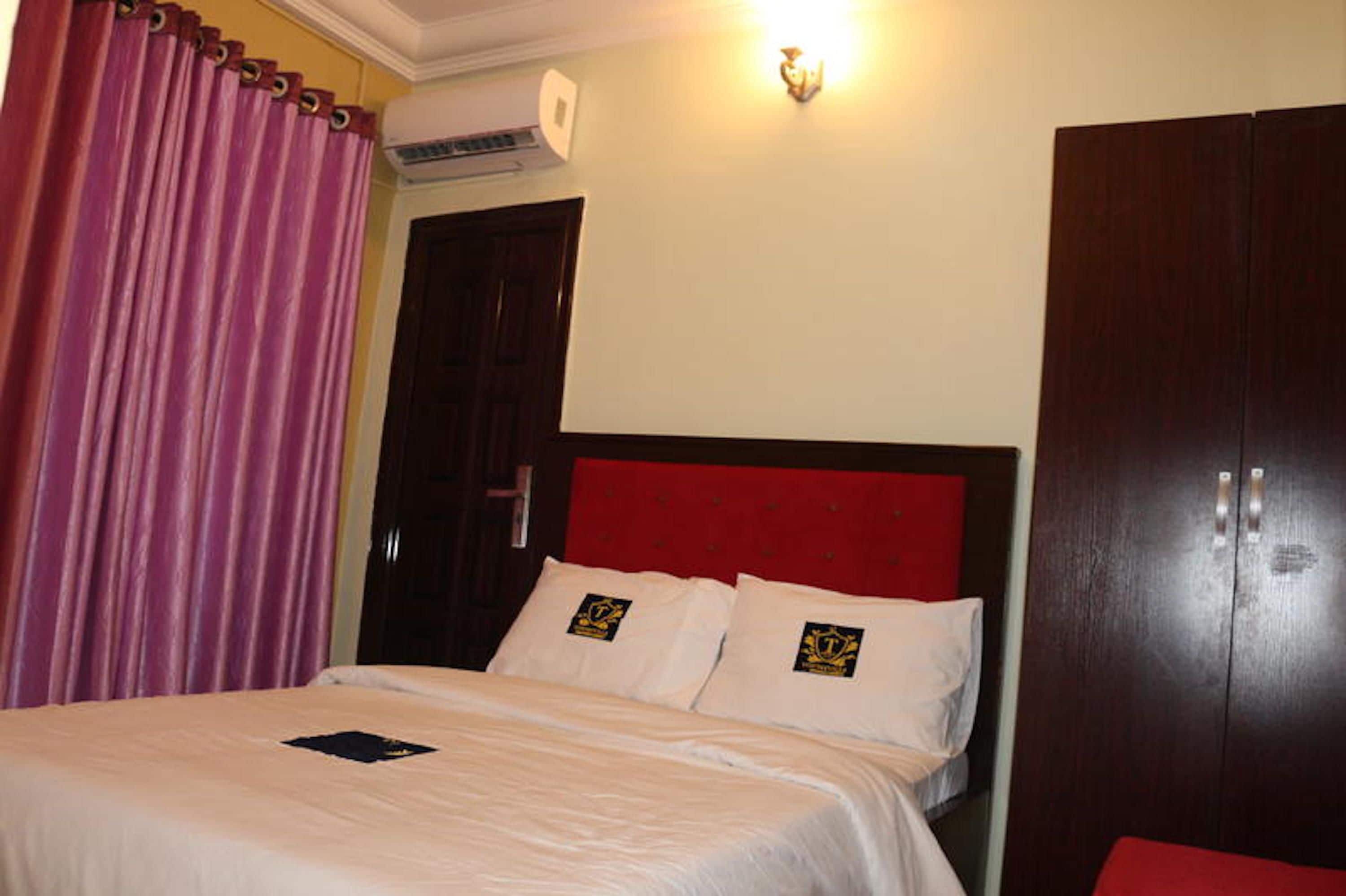 Una habitación de hotel con una cama, un armario y una cortina.